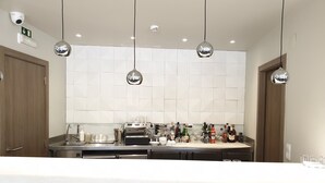 Una cocina moderna con una isla central, electrodomésticos de acero inoxidable y lámparas colgantes.