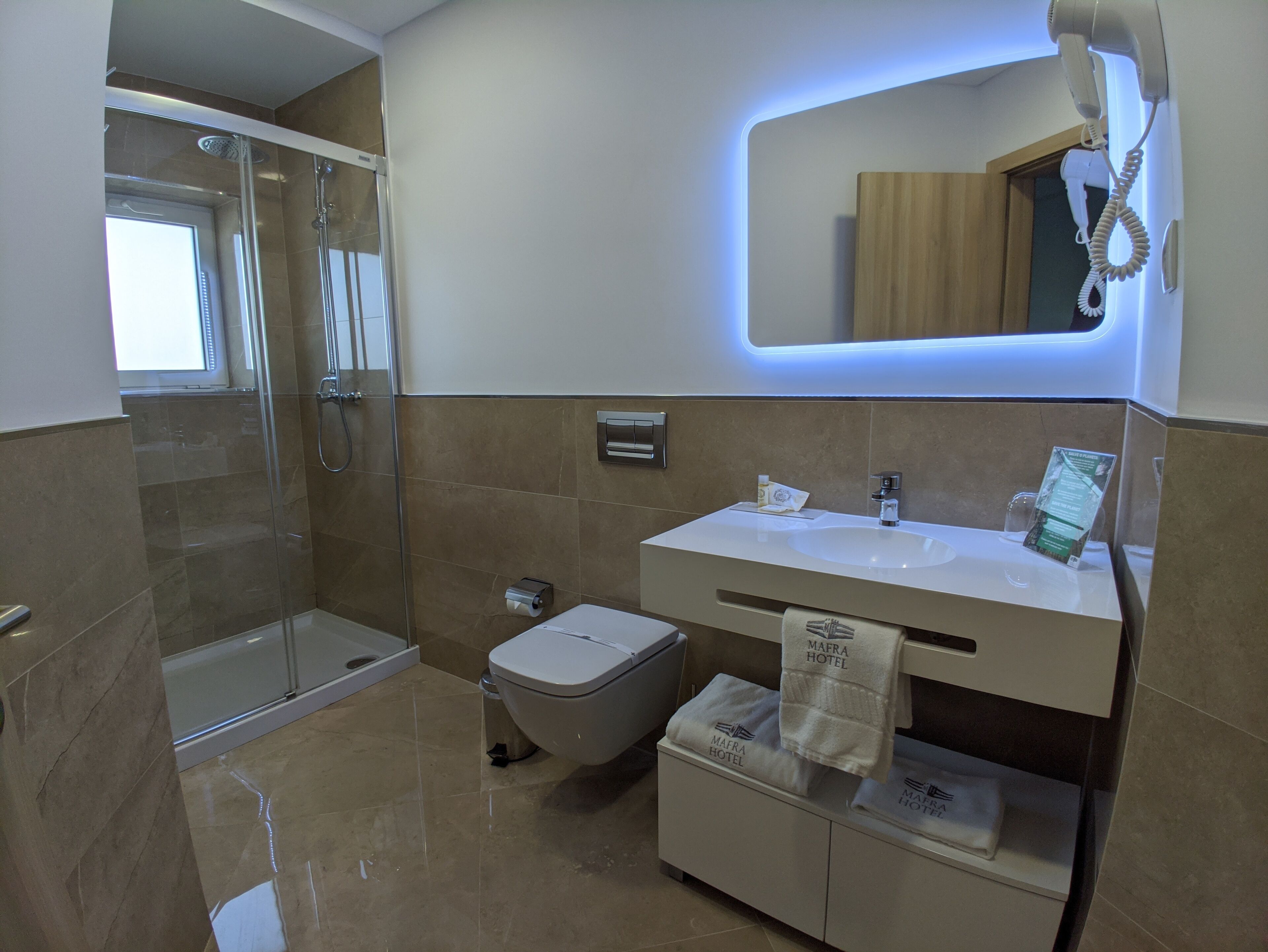 Un bagno moderno con box doccia in vetro, un lavandino bianco con specchio sopra e un water con portasciuga.