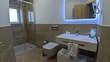 Un bagno moderno con box doccia in vetro, un lavandino bianco con specchio sopra e un water con portasciuga.