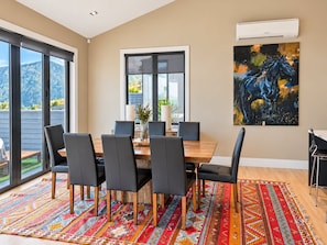 Een eethoek met een houten tafel, zwarte stoelen en een kleurrijk vloerkleed.