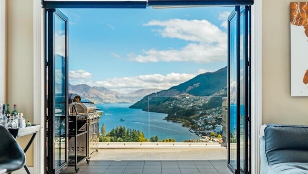 Un balcon avec vue sur un lac et des montagnes, un barbecue et un canapé.