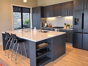 Una cocina moderna con una isla grande, muebles oscuros y una pared decorativa de piedra.