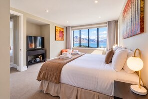 Ein Hotelzimmer mit einem großen Bett, einem Fernseher, Blick auf Berge und einem Bild an der Wand.