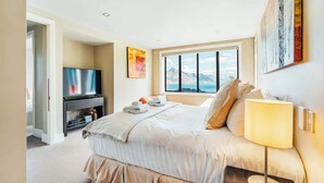 Une chambre d’hôtel moderne dotée d’un grand lit, d’une télévision, d’une fenêtre donnant sur les montagnes et d’œuvres d’art accrochées aux murs.