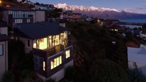 Une maison moderne dotée d’un balcon donnant sur un paysage montagneux et un plan d’eau.