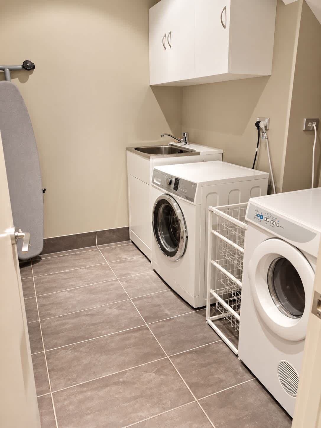 A compact laundry room with a washing machine, dryer, and a small sink.