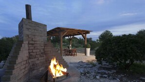 A brick fire pit with a wooden pergola and outdoor seating area. - Monolocale del Sole (Morciano di Leuca)