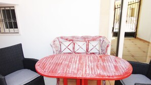 A red wooden table with a glass top, surrounded by two black wicker chairs with grey cushions. - VersoSud - Casa Torre San Giovanni 17 (Ugento)