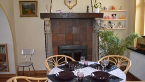 A dining room with a fireplace, a table set for four, and a bookshelf in the background. - Home Trietje Ghent (Ghent)