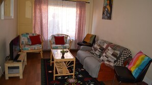 A cozy living room with a sofa, two armchairs, a coffee table, and a television. - Home Trietje Ghent (Ghent)