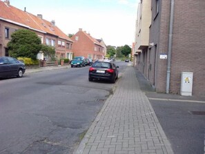 En boligvej med huse, parkerede biler og fortov.