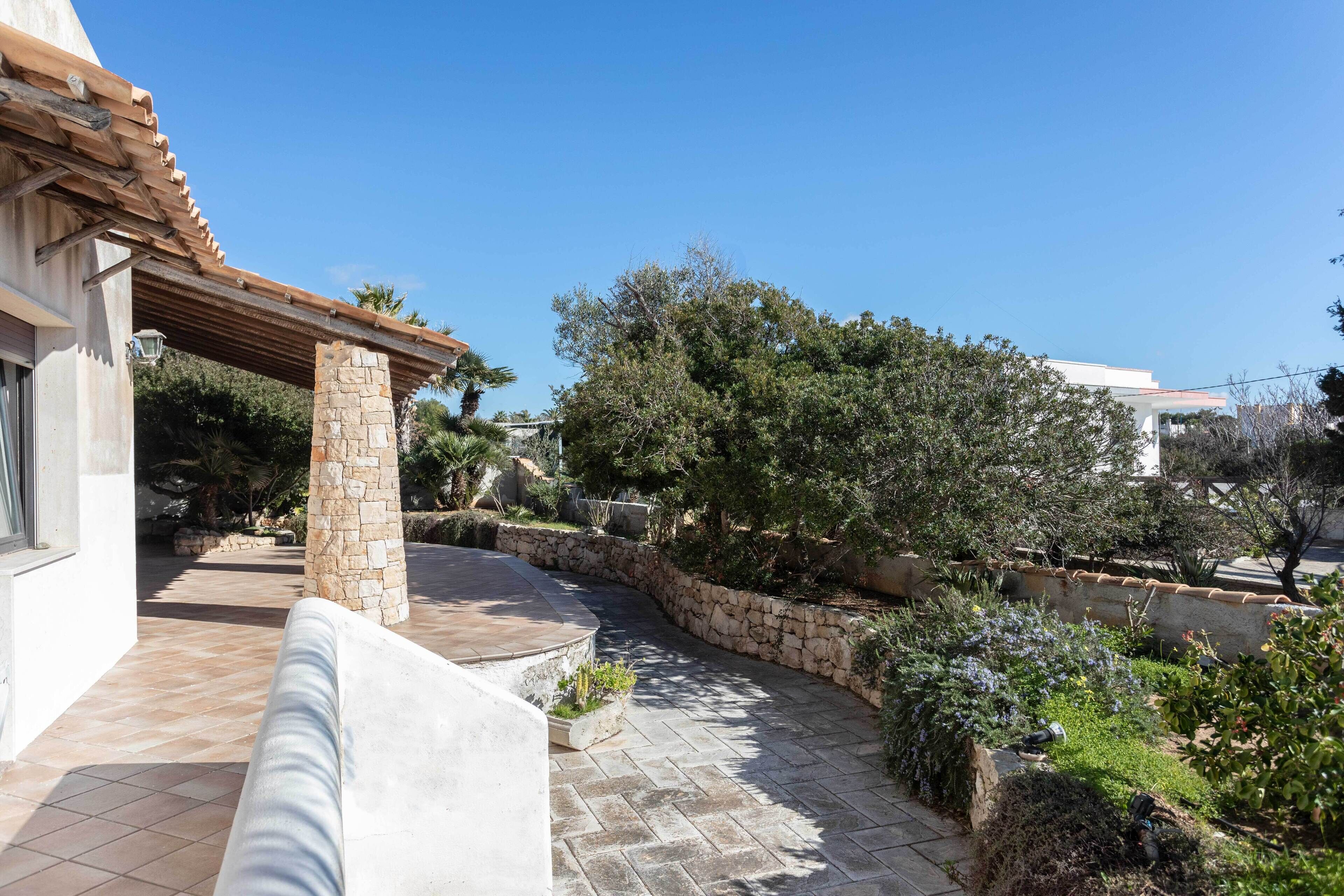 Ein Innenhof mit Steinmauer, einer Pergola und verschiedenen Pflanzen.