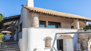 A white building with a tiled roof, stone pillars, and arched doorways. - Emma's Villa facing the sea with swimming pool (Racale)