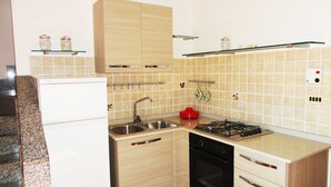 Una cocina compacta con lavamanos, estufa, horno y armarios.
