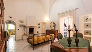A room with a bed, a dining table, chairs, a fireplace, and a mirror. - Palazzo Raheli (Gallipoli)