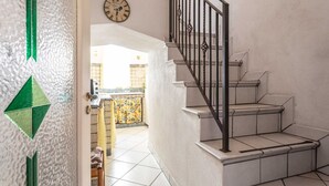 A staircase with a metal railing and a view of a kitchen area with a tiled floor and a yellow patterned curtain. - Palazzo Raheli (Gallipoli)