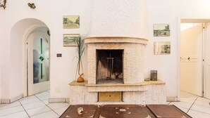 A room with a fireplace, a door with a glass panel, and framed pictures on the wall. - Palazzo Raheli (Gallipoli)