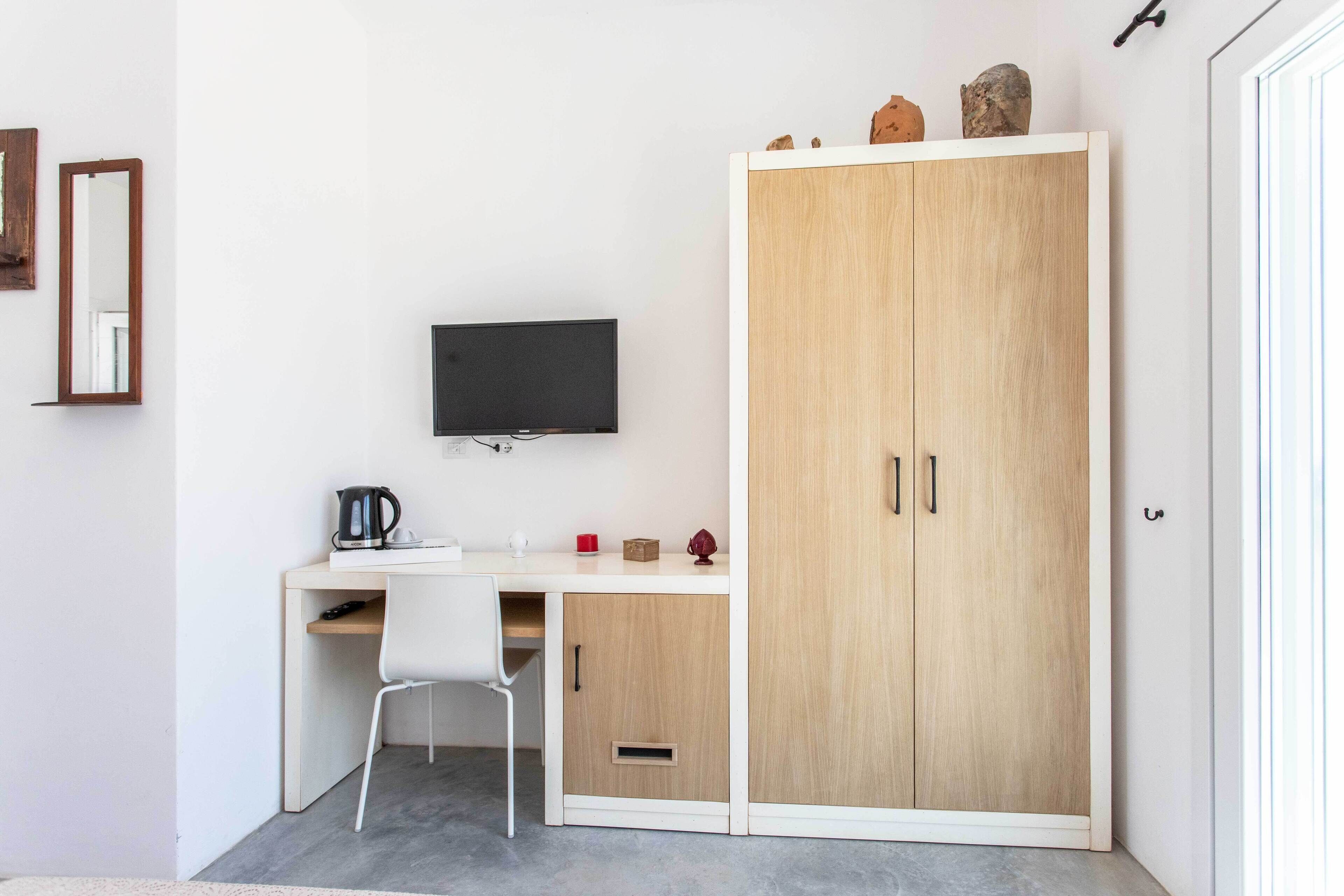 Une chambre équipée d’un bureau, d’une chaise, d’une télévision, d’une armoire et d’une machine à café.