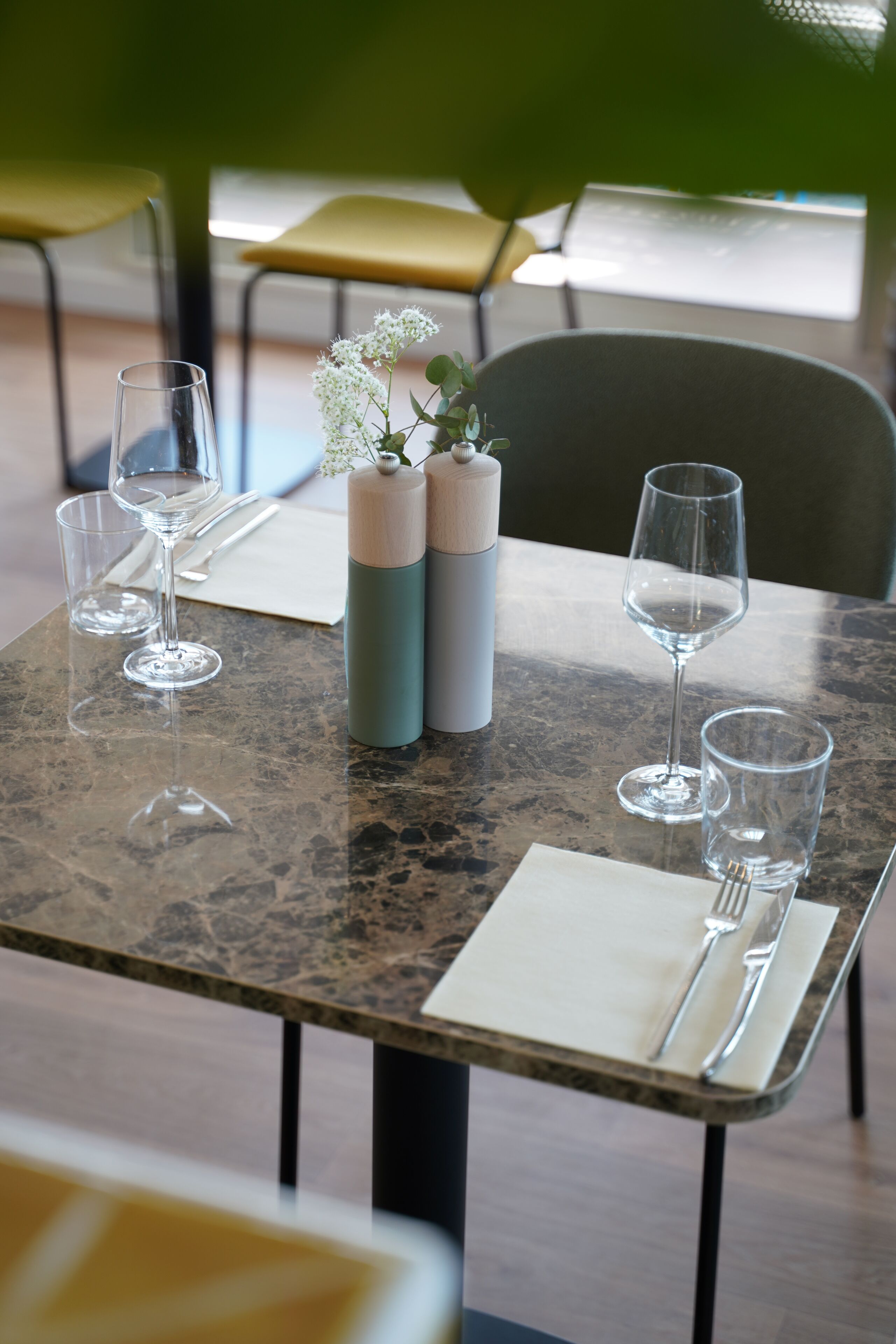 Et bord dækket til to personer med en vase med blomster, to glas og en vandflaske.