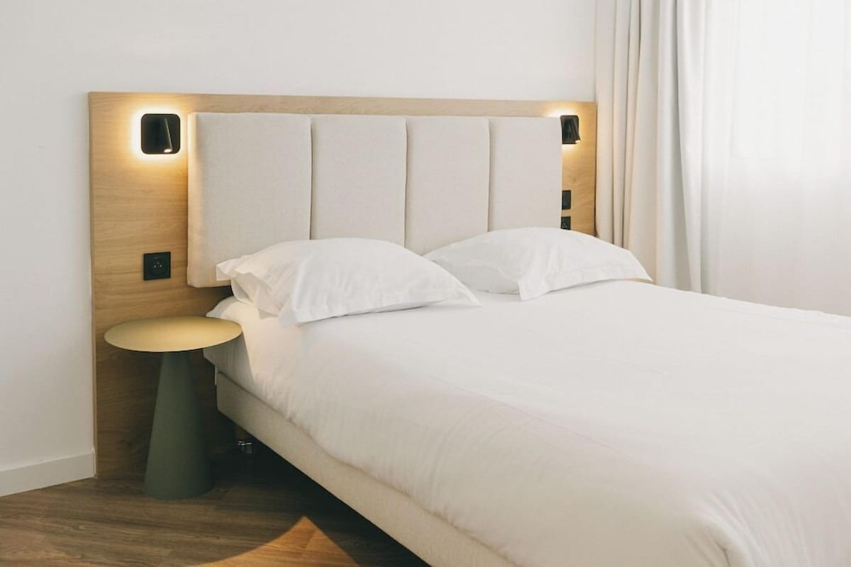 A neatly made bed with a wooden headboard and bedside table.