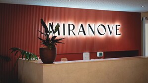 Un mostrador de recepción con una planta en maceta y un letrero que dice "MIRANOVE".