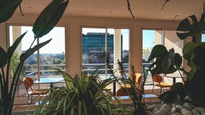 Un interior moderno con ventanas amplias, plantas de interior y vistas a un paisaje urbano.