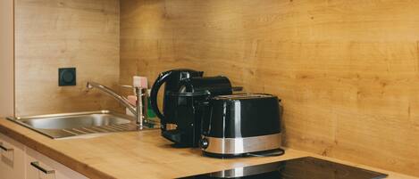 A kitchen with a wooden countertop, a sink, a coffee maker, and a toaster.