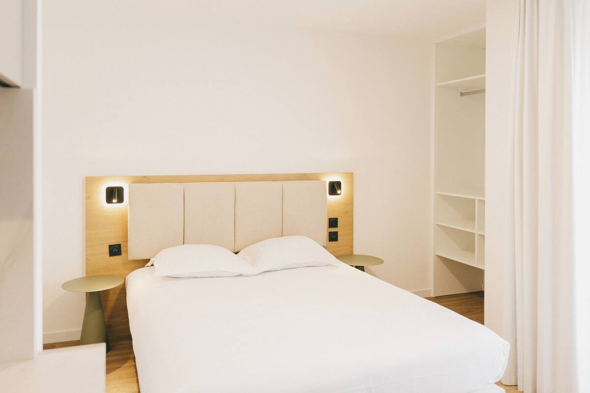 Une chambre d’hôtel moderne avec un grand lit, des tables de chevet et une armoire intégrée.