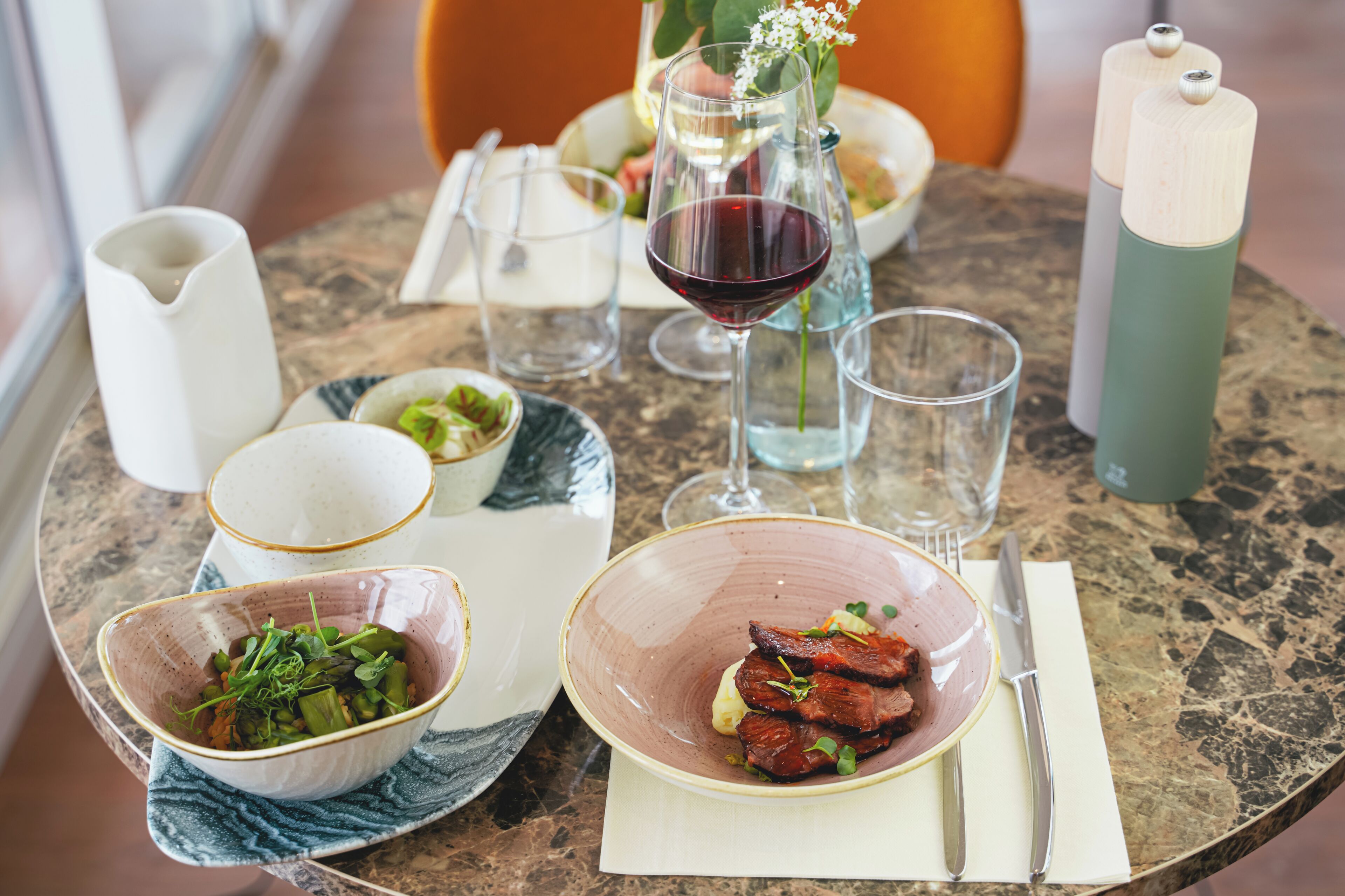 Una mesa de comedor con diferentes platos, una copa de vino y una vela.