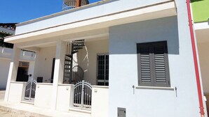 A two-story building with a covered porch, a spiral staircase, and a metal gate. - VersoSud - Appartamento Colaianni 24 (Ugento)