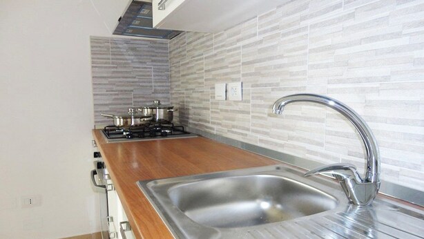 A kitchen with a stainless steel sink, wooden countertop, and a gas stove. - VersoSud - Appartamento Colaianni 24 (Ugento)