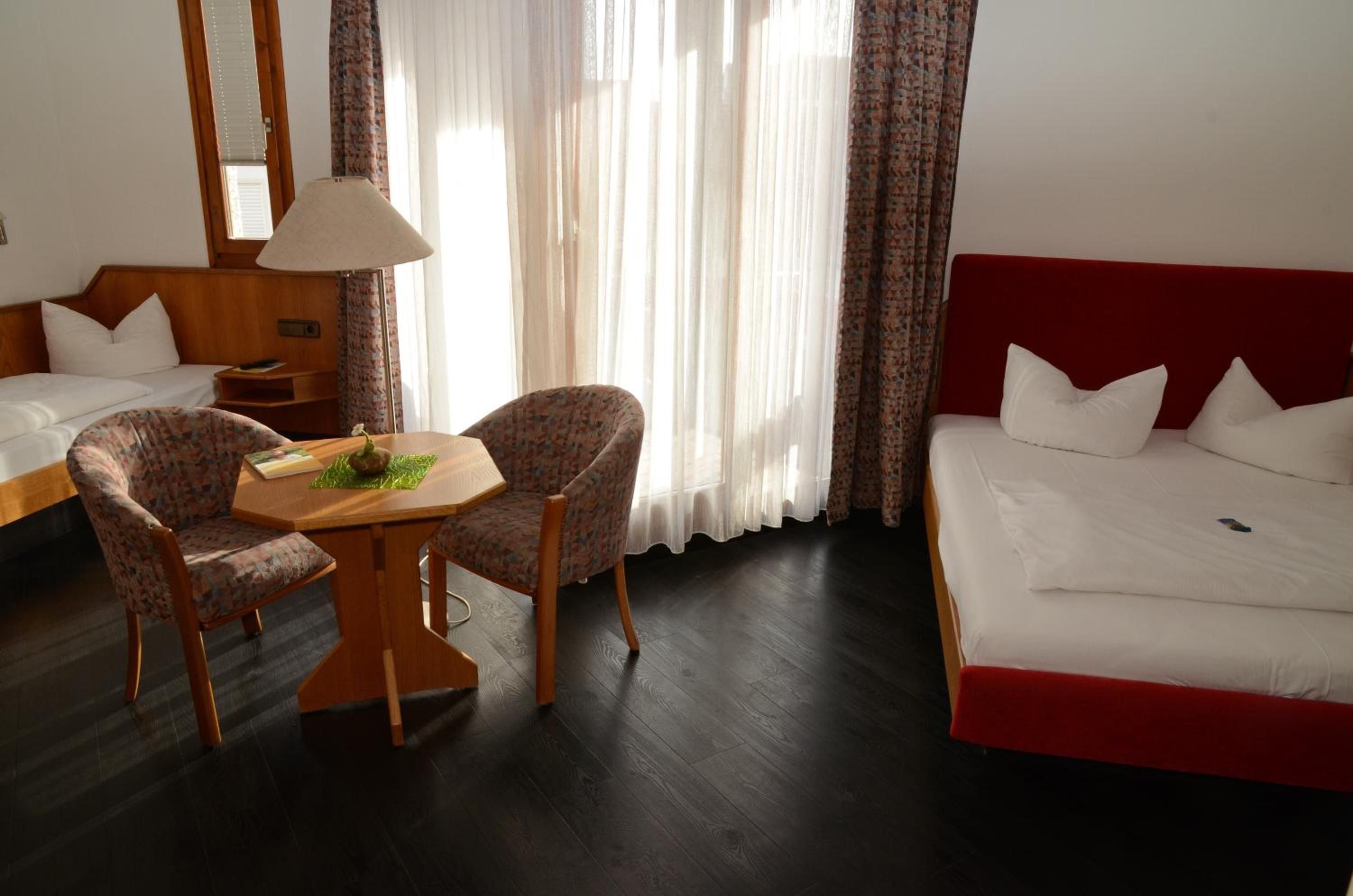 Una habitación de hotel con una cama, dos sillas, una mesa y una lámpara.