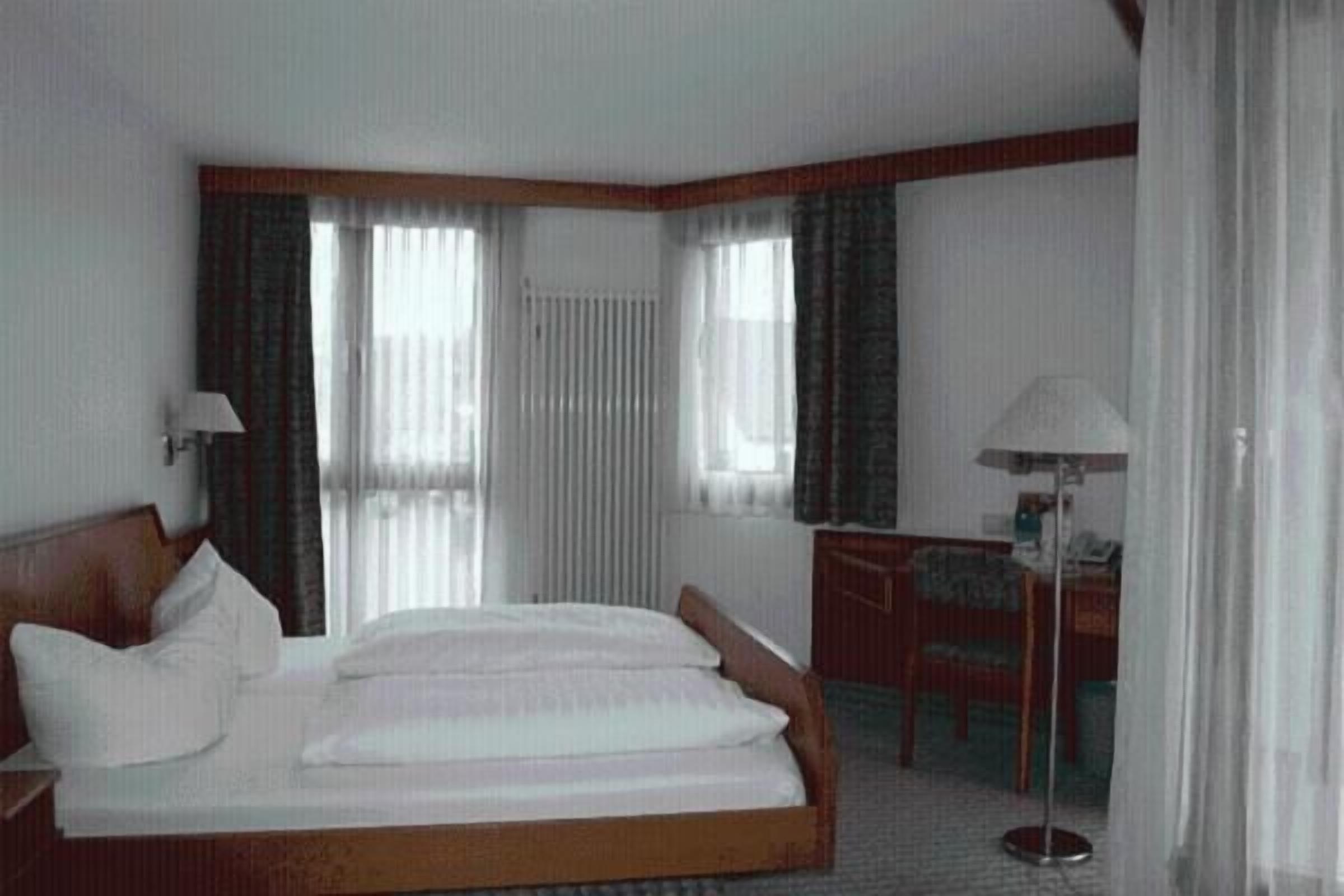 Una habitación de hotel con una cama, un escritorio y una silla.