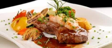 Un plato de comida con un filete, verduras y una guarnición.