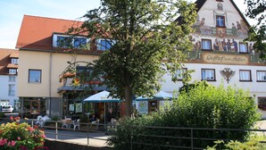 A building with a traditional facade, outdoor seating, and a tree in the foreground.