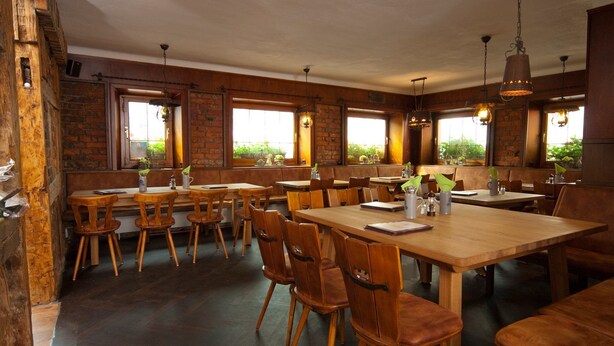 A restaurant with wooden tables and chairs, brick walls, and large windows.