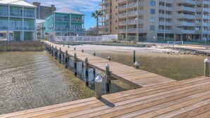 Une propriété située au bord de l’eau, avec une promenade en bois menant à un bâtiment doté de plusieurs balcons.