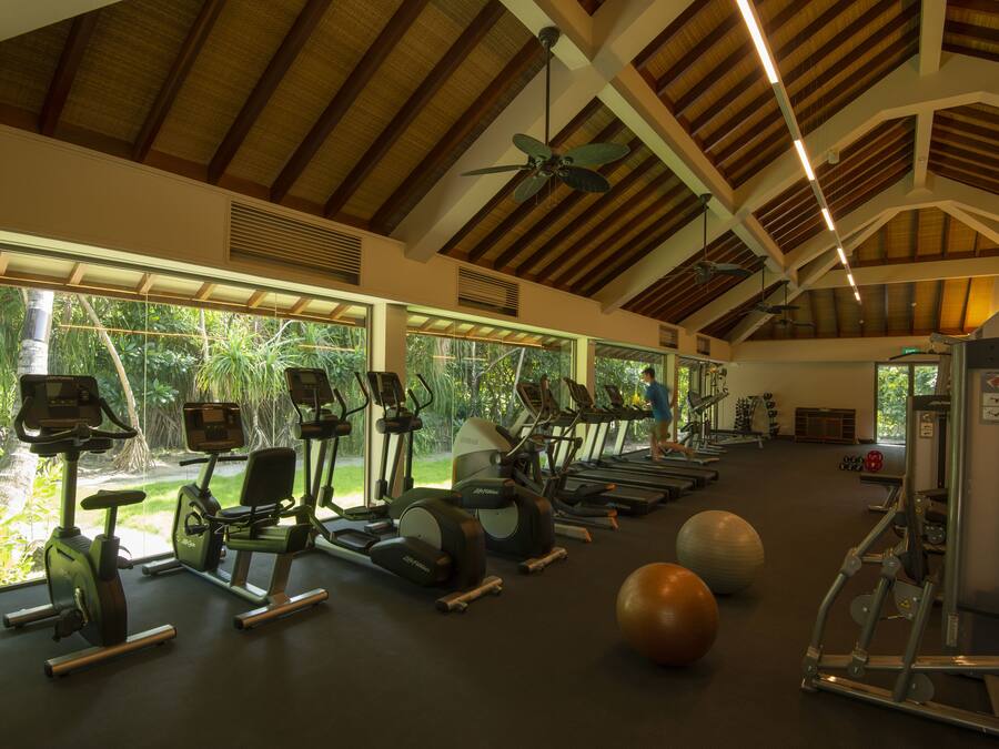 A gym with exercise equipment, large windows, and a high ceiling.