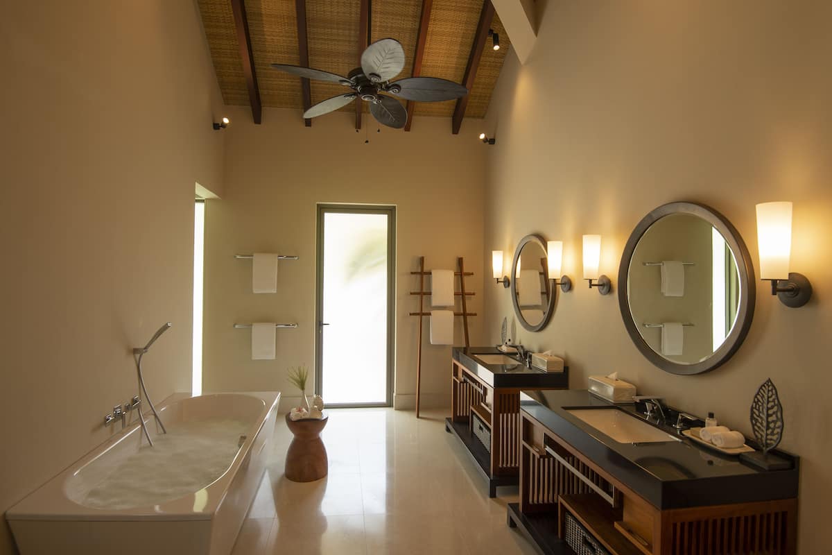 A modern bathroom with a freestanding bathtub, a vanity with a mirror, and two wall-mounted lights.