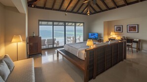 Um quarto espaçoso com uma cama grande, uma escrivaninha, uma televisão e um ventilador de teto.