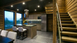 Una cocina moderna con una isla central, taburetes de bar y un refrigerador de acero inoxidable.