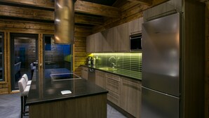 Una cocina moderna con armarios de madera, un refrigerador de acero inoxidable y una isla central con pileta y hervidor.