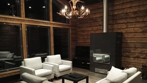 Una sala de estar moderna con chimenea, sofás de cuero y una araña.