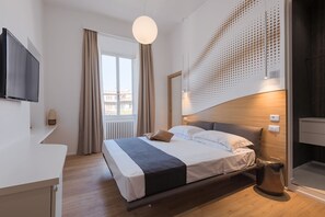 Una habitación de hotel moderna con una cama grande, un televisor de pantalla plana, un escritorio y un balcón con cortinas.