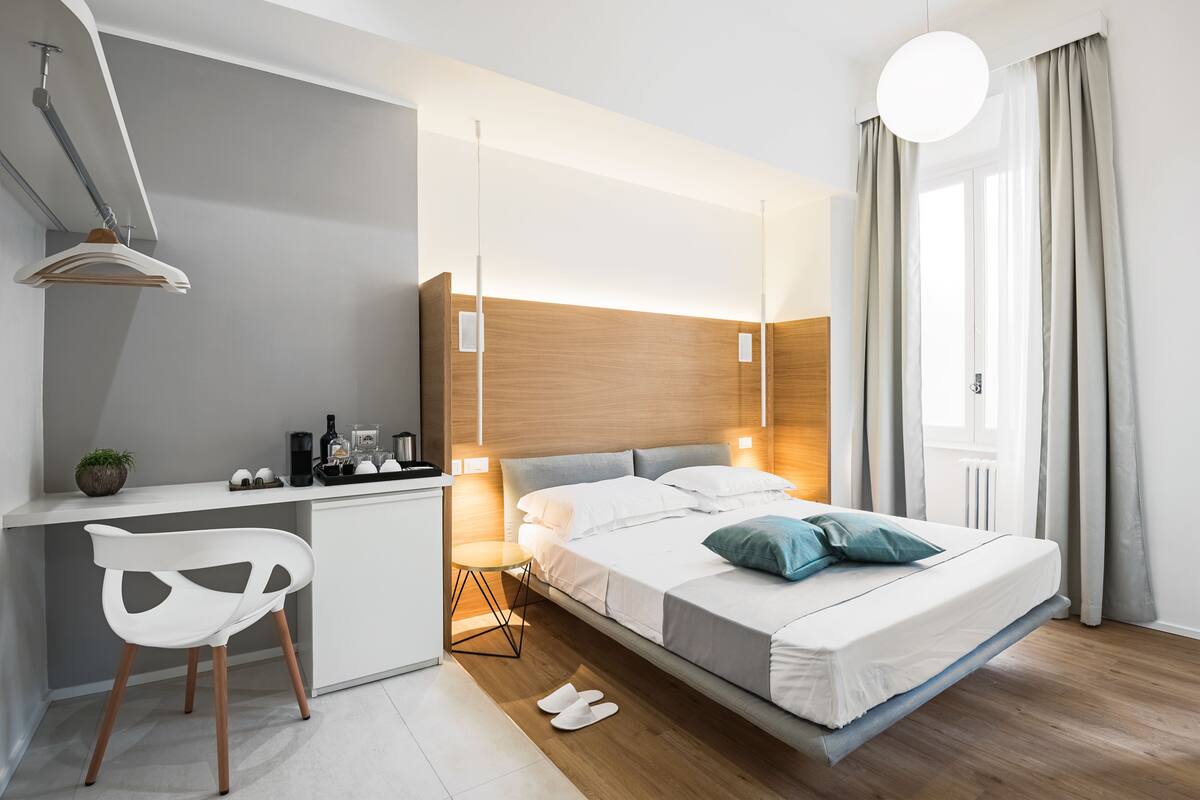A modern hotel room with a bed, desk, and chair.