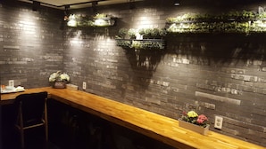 A restaurant with a long wooden counter, brick walls, and hanging planters with greenery. - Hotel Yaja Jongno (Seoul)