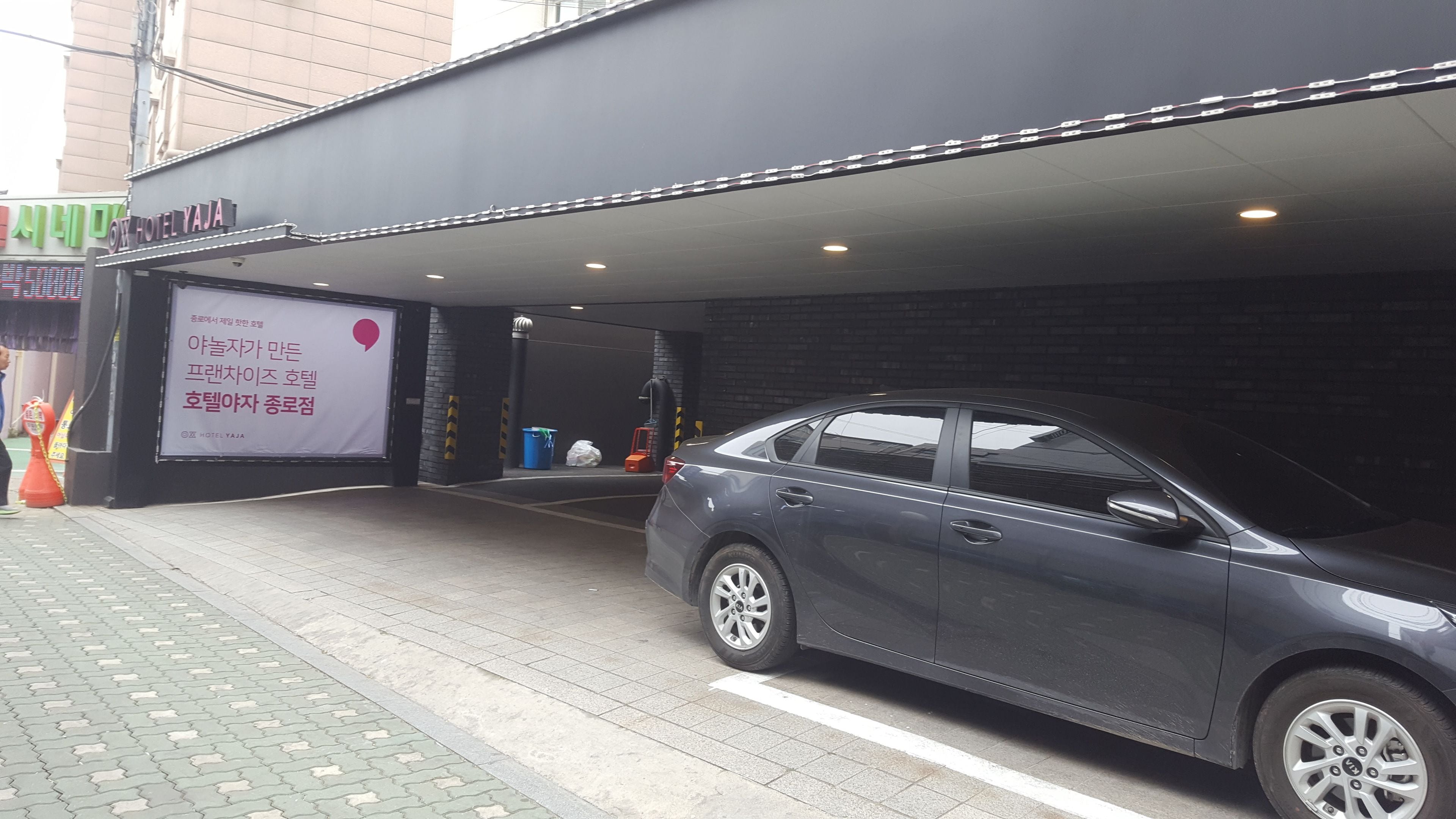 A hotel entrance with a car parked in front.