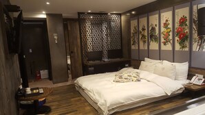 A hotel room with a large bed, a desk with two computers, a decorative screen, and a wall with floral artwork. - Hotel Yaja Jongno (Seoul)