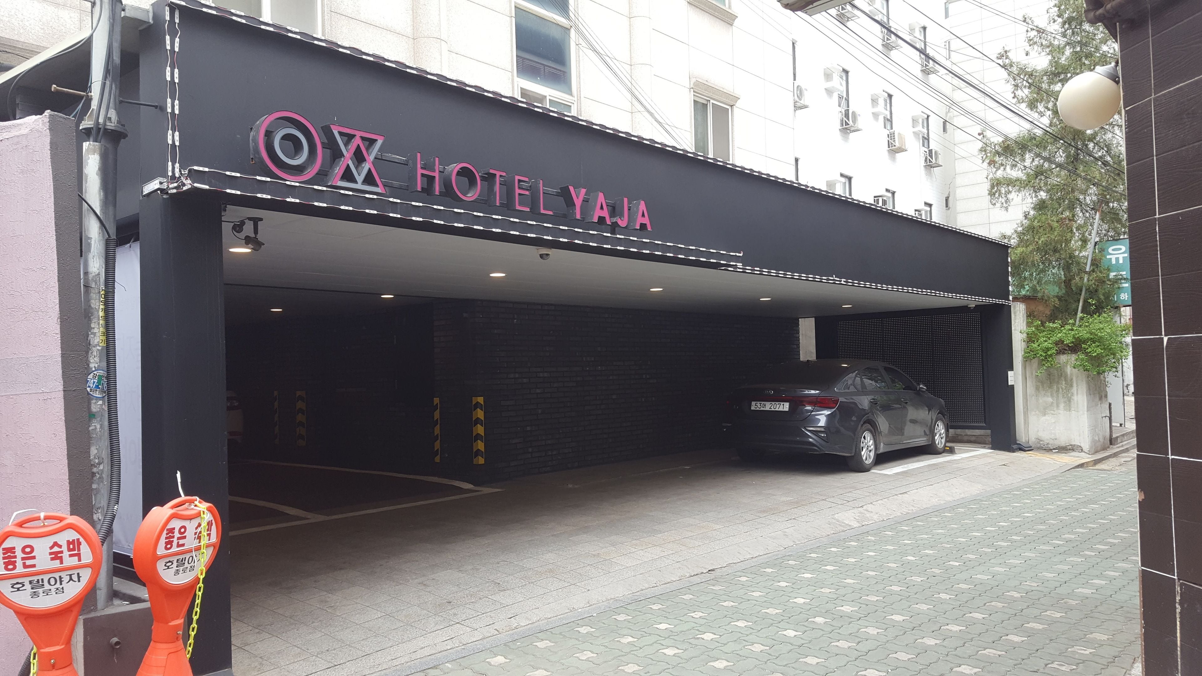 A hotel entrance with a black facade and a car parked inside.