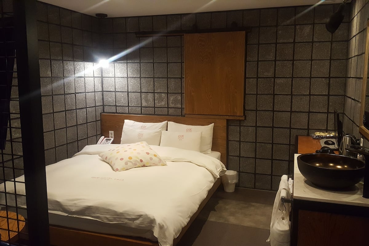 Une chambre à coucher avec un lit, une table de chevet et un grand miroir.